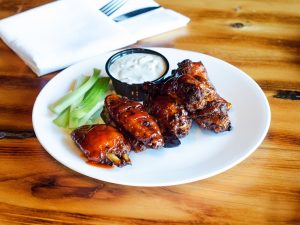 Chicken wings on a plate with celery and dipping sauce.