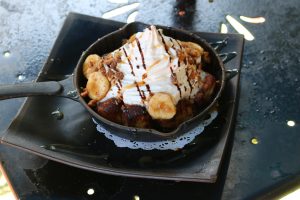 A dish with whipped cream and bananas on a plate.