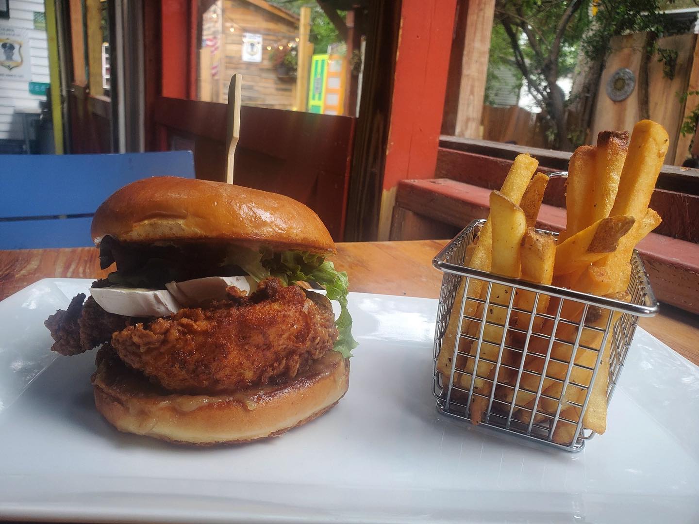 A chicken sandwich with french fries on a white plate.