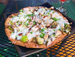 A pizza with brussels sprouts and chicken on a plate.