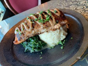 A plate of salmon and mashed potatoes on a table.