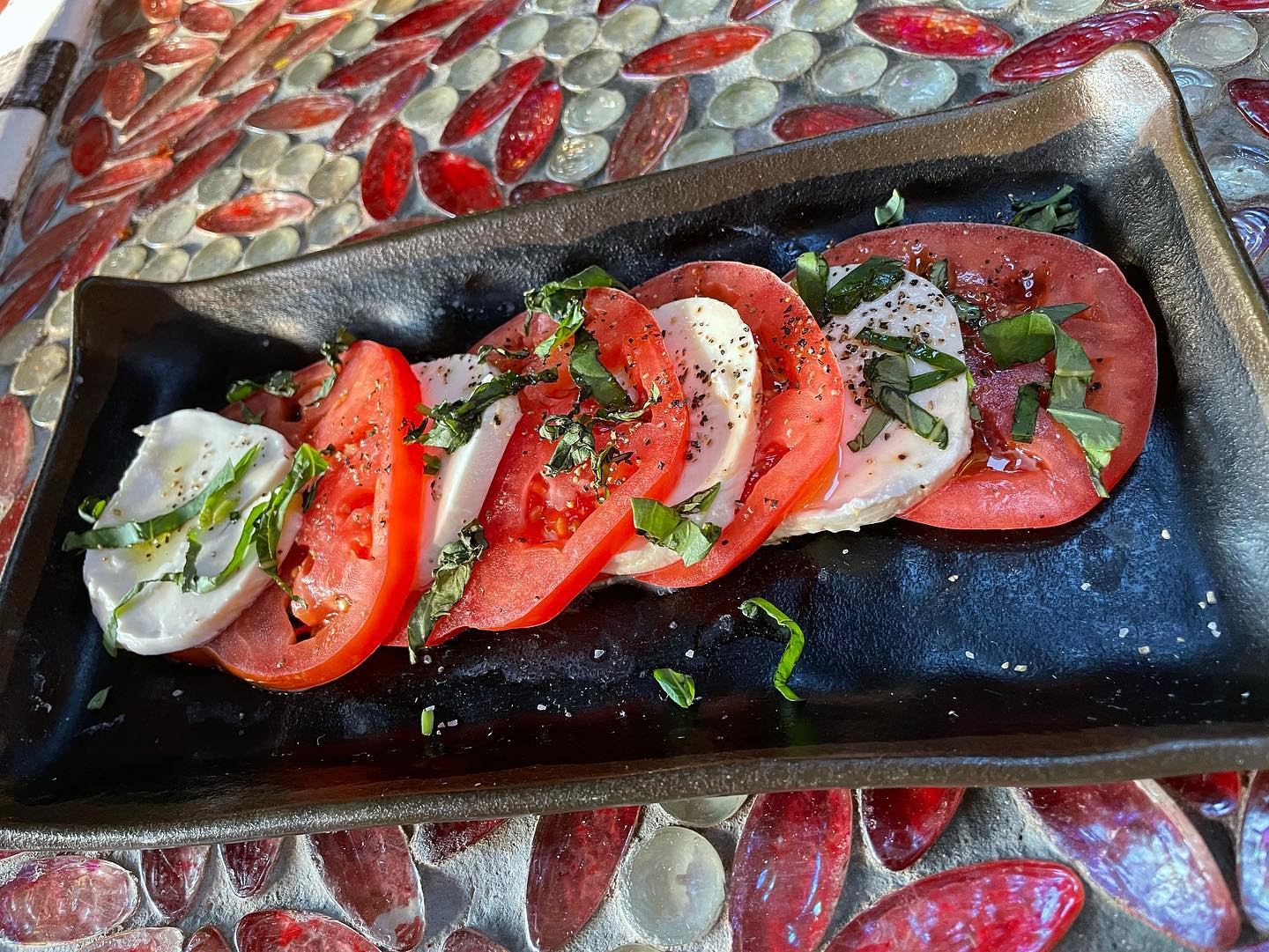 A plate with tomatoes and basil on it.