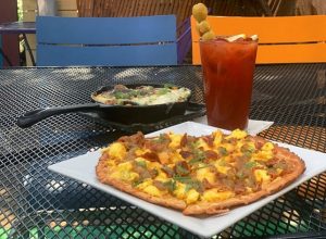 A plate of pizza and a drink on an outdoor table.