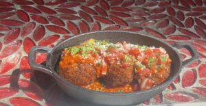 Meatballs in a pot on a red tiled floor.