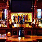 An ornate bar with stools and a tv.